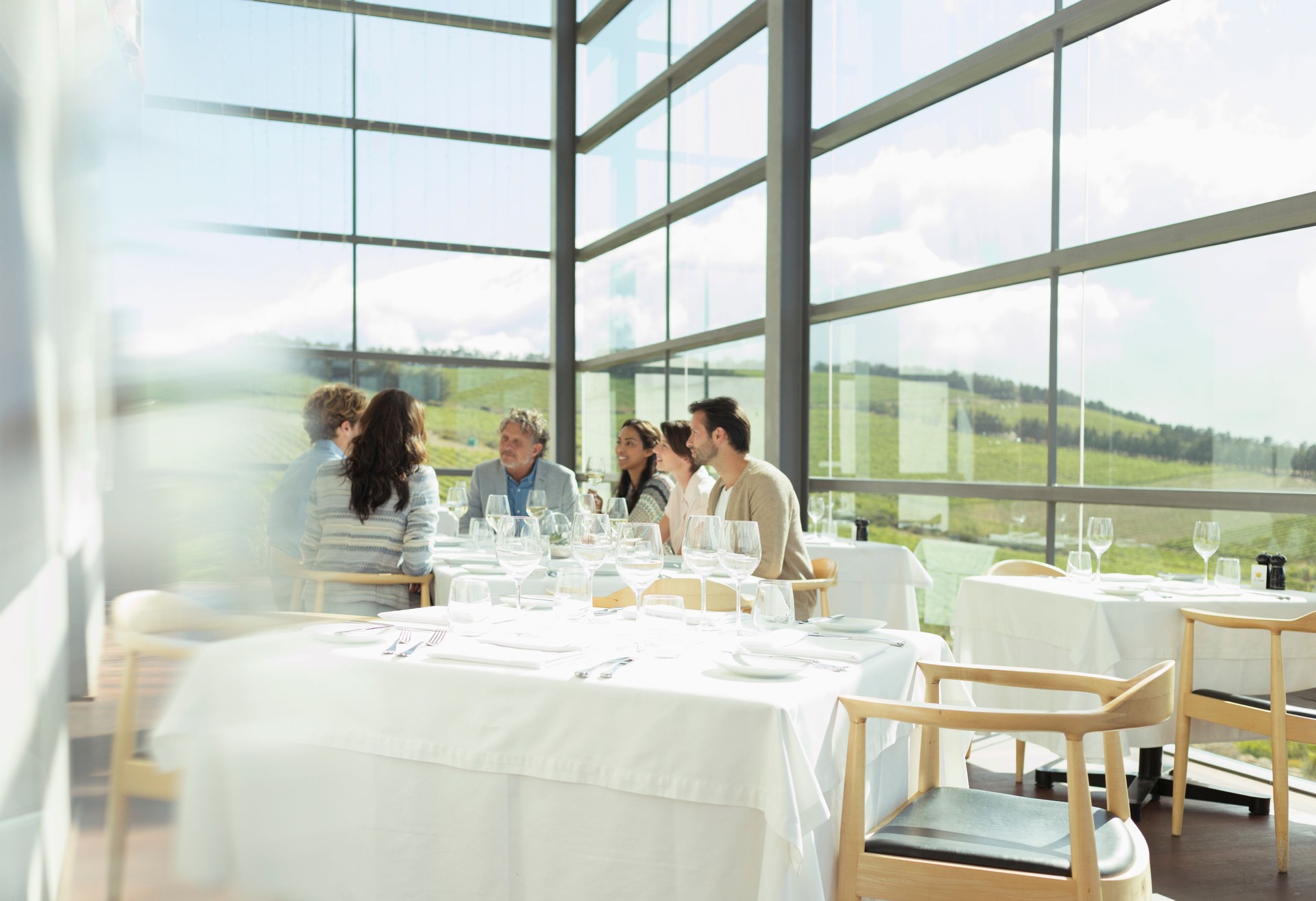 Friends sitting at table in sunny winery dining room